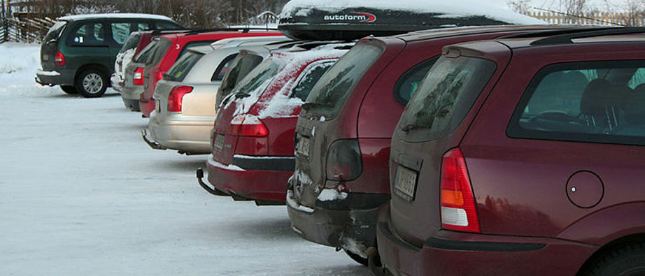 Bilar med snö på sig står parkerade i rad